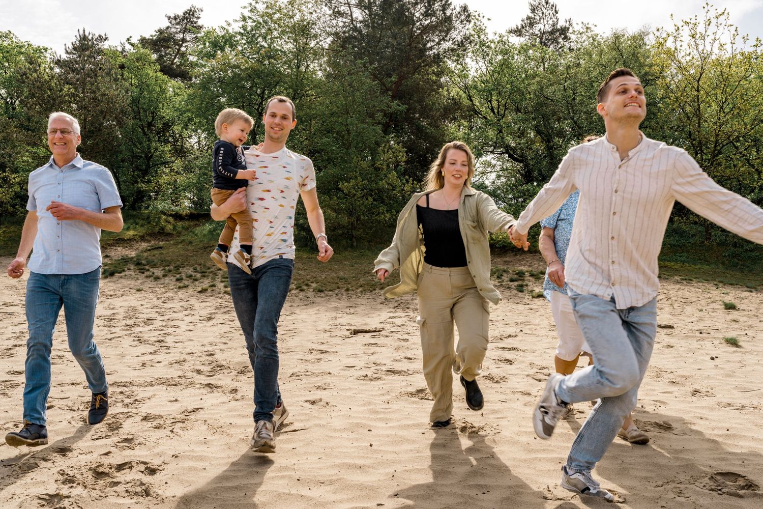 A group of people walking together on a sandy beach path surrounded by nature.