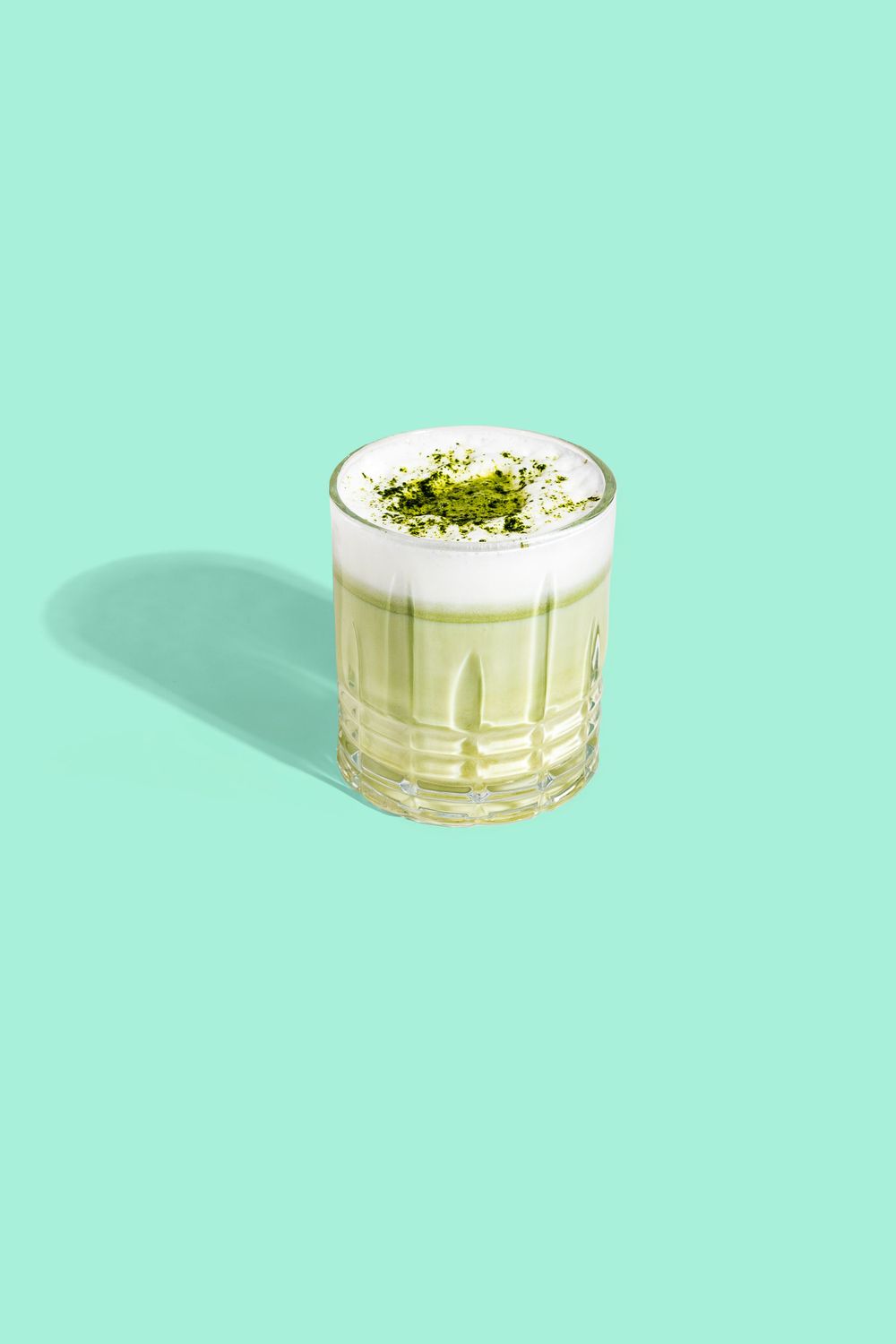 Matcha latte topped with green powder in a crystal glass against mint background. Mtlshutter photography