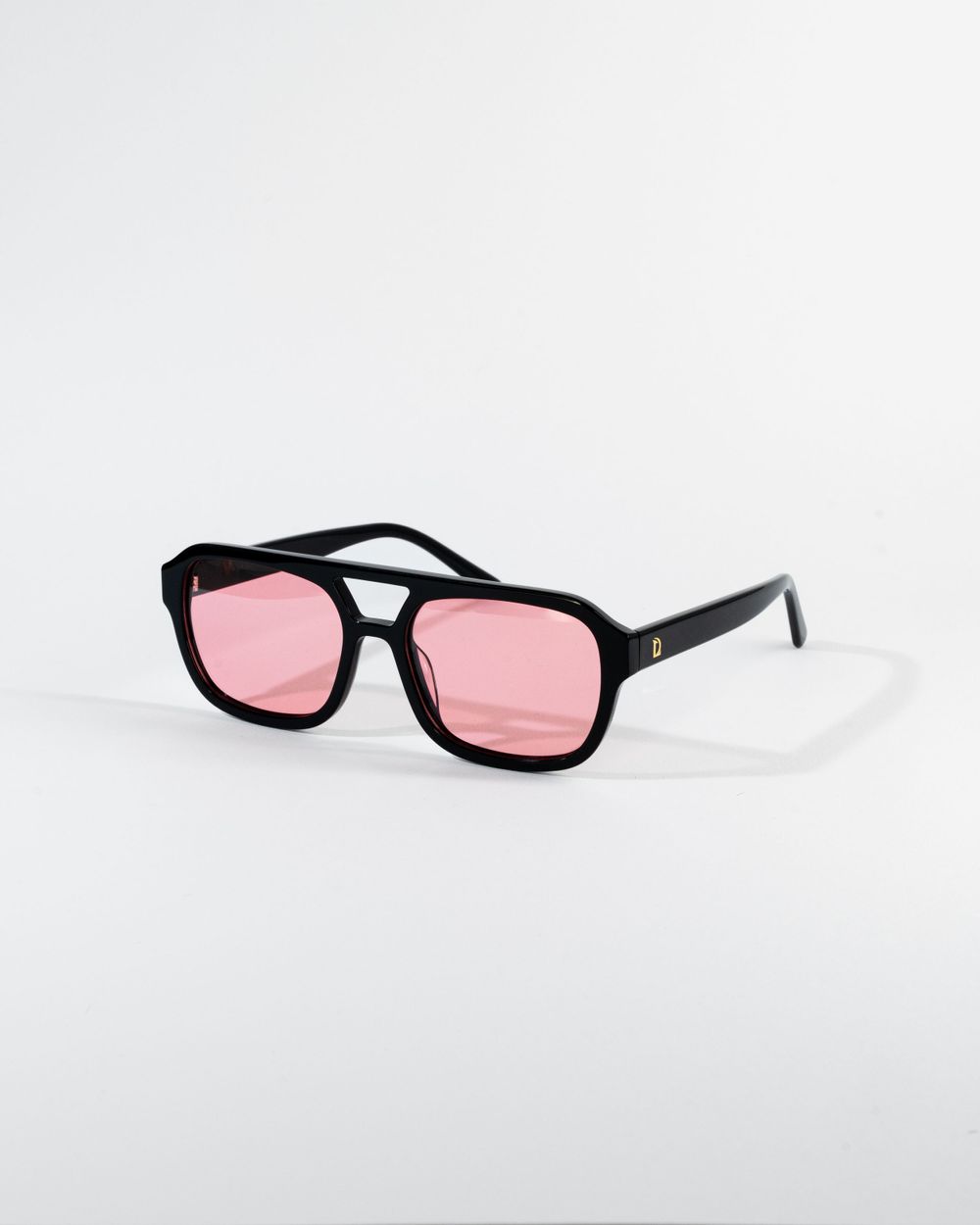 Black retro-style sunglasses with pink-tinted lenses photographed on white background. Mtlshutter photography