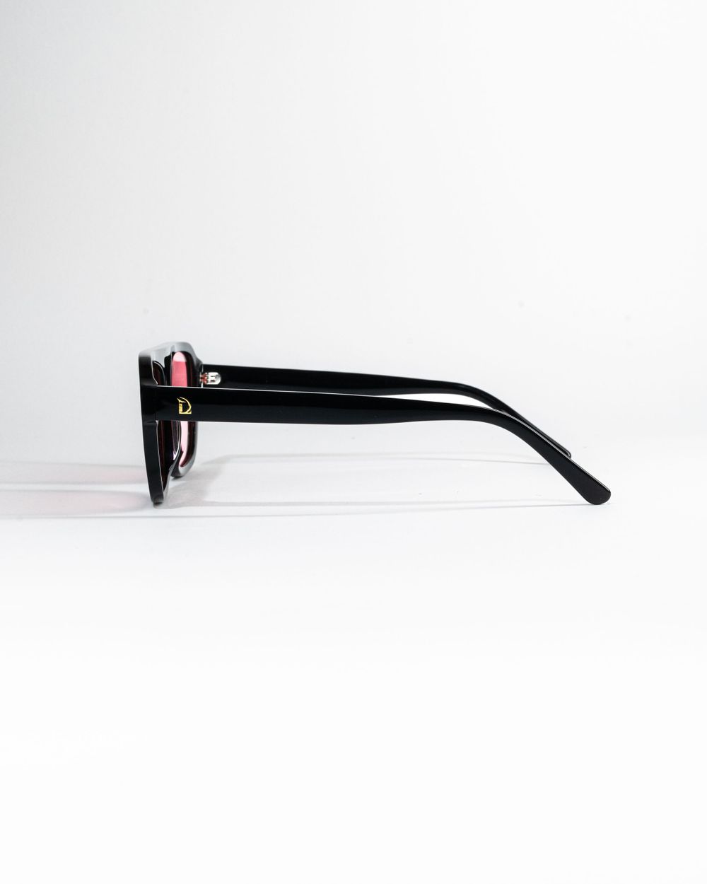 Side view of black sunglasses frame showing temple arm detail against white background. Mtlshutter photography