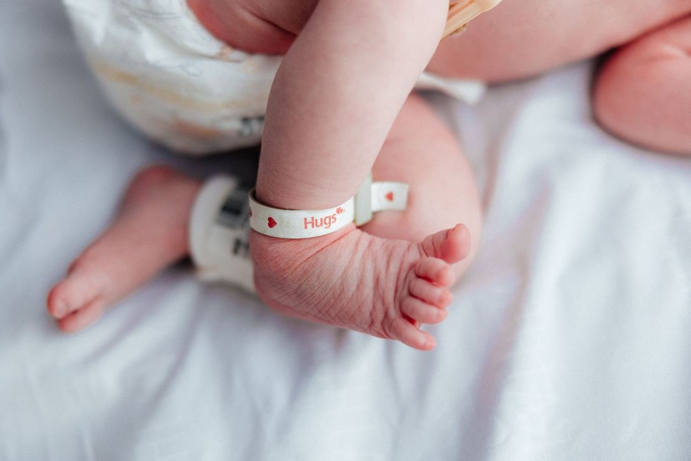 Close-up of a newborn's tiny feet with hospital identification bands.