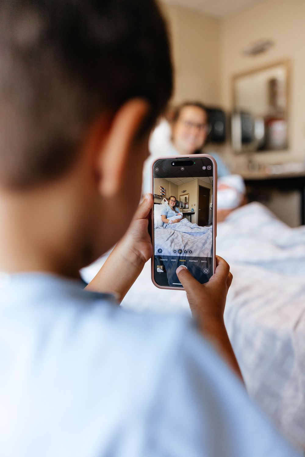 Someone taking a photo with a smartphone of a hospital patient in a medical bed.
