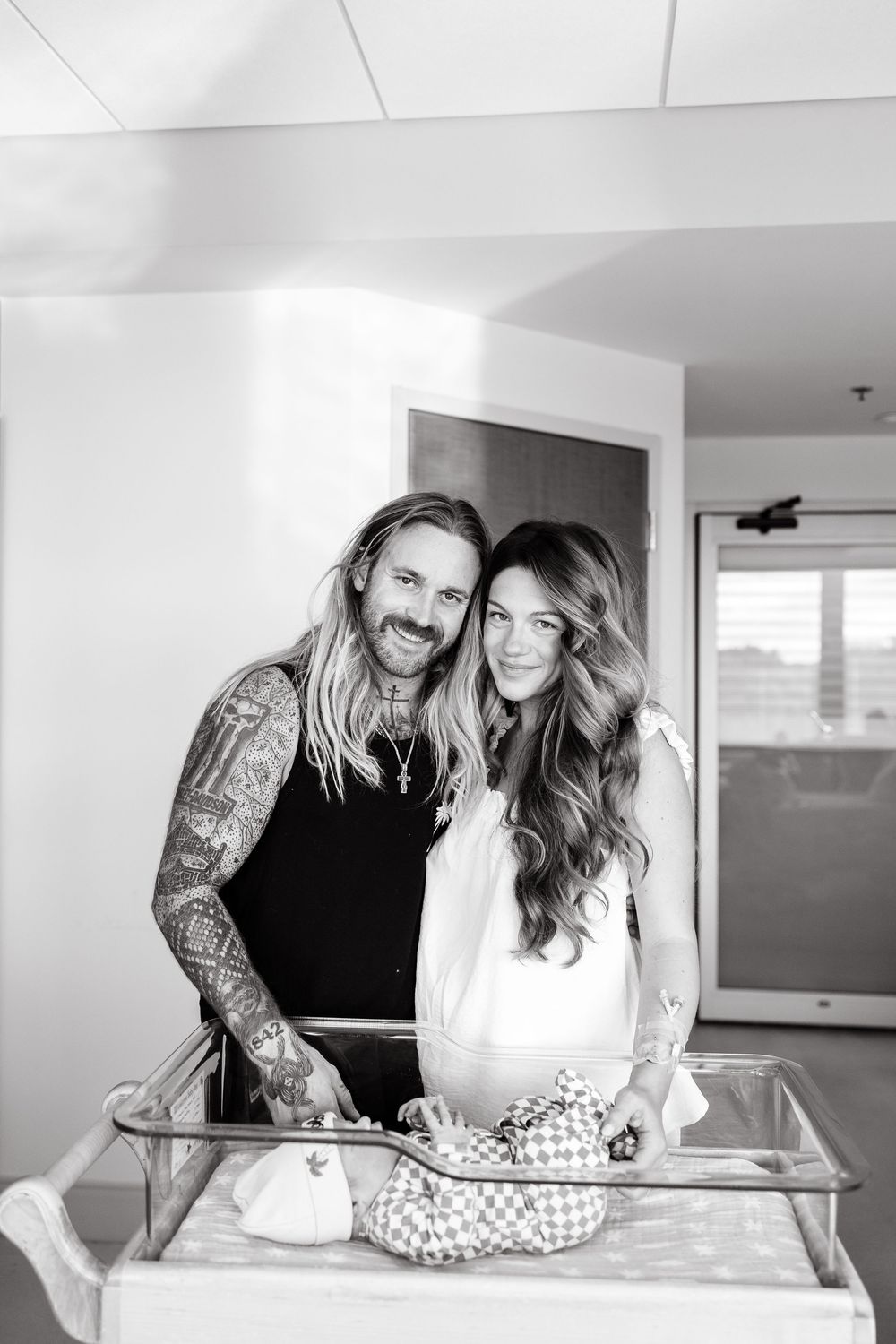 A couple shares a tender moment while standing at a glass counter in a bright modern space.
