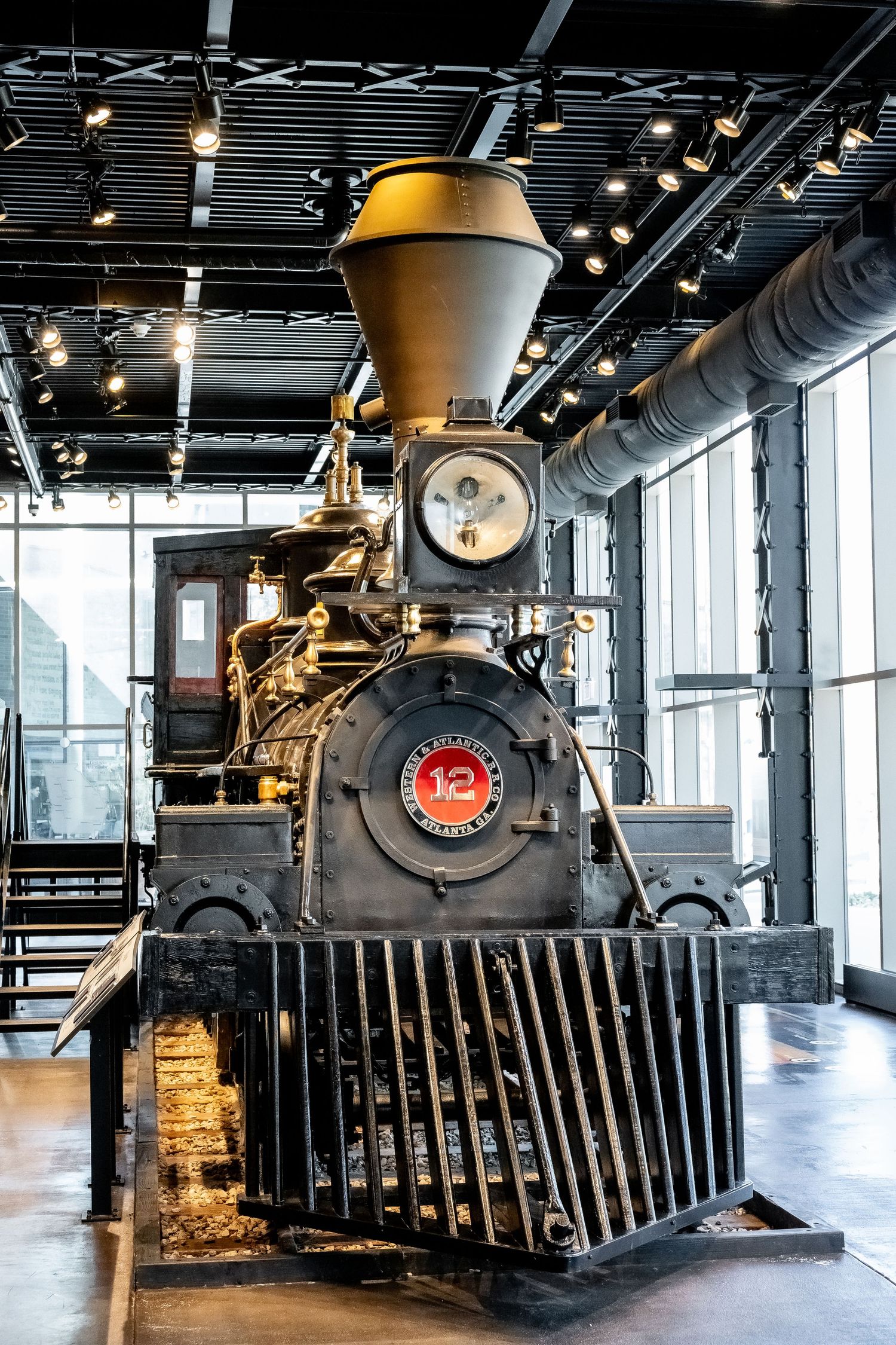 Historic black steam locomotive with yellow funnel displayed in museum gallery.