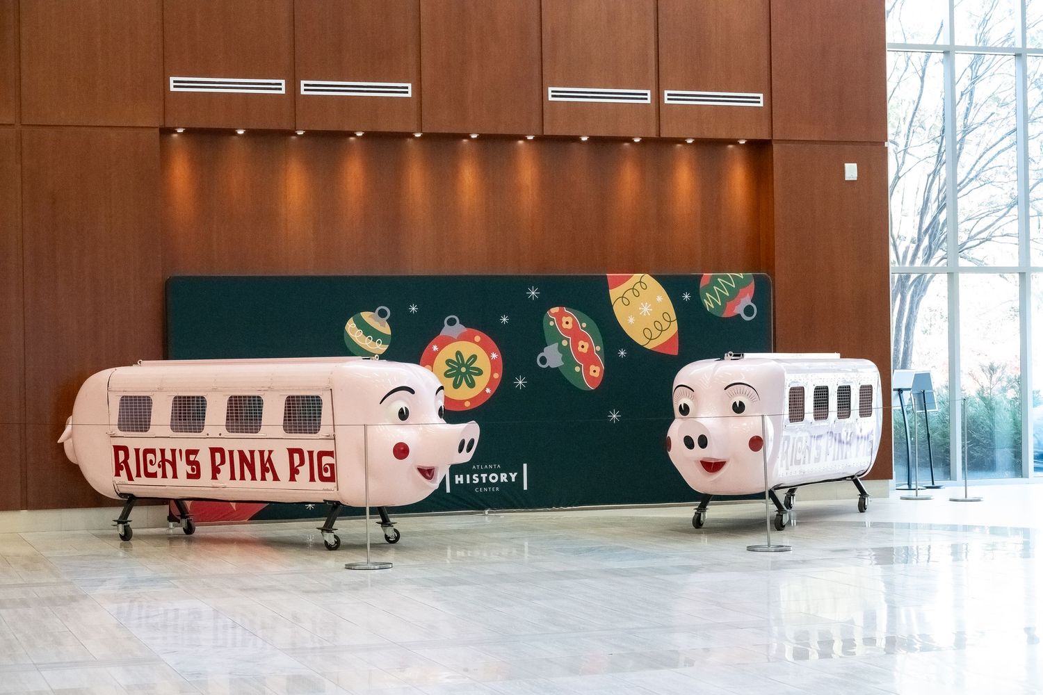 Pink pig-shaped train cars displayed as decorative pieces against a dark green wall.