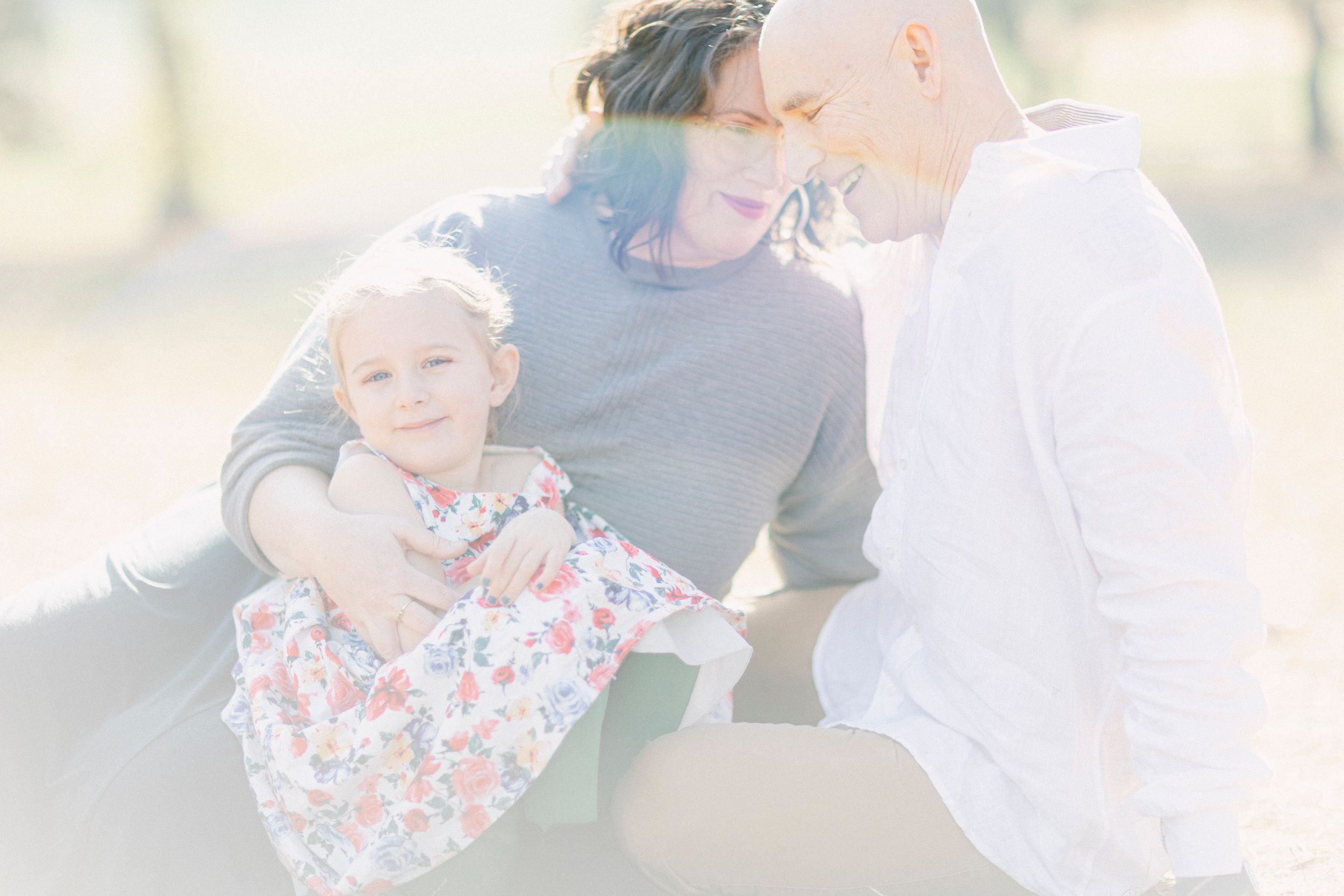 A family shares a playful moment together outdoors in ethereal lighting.