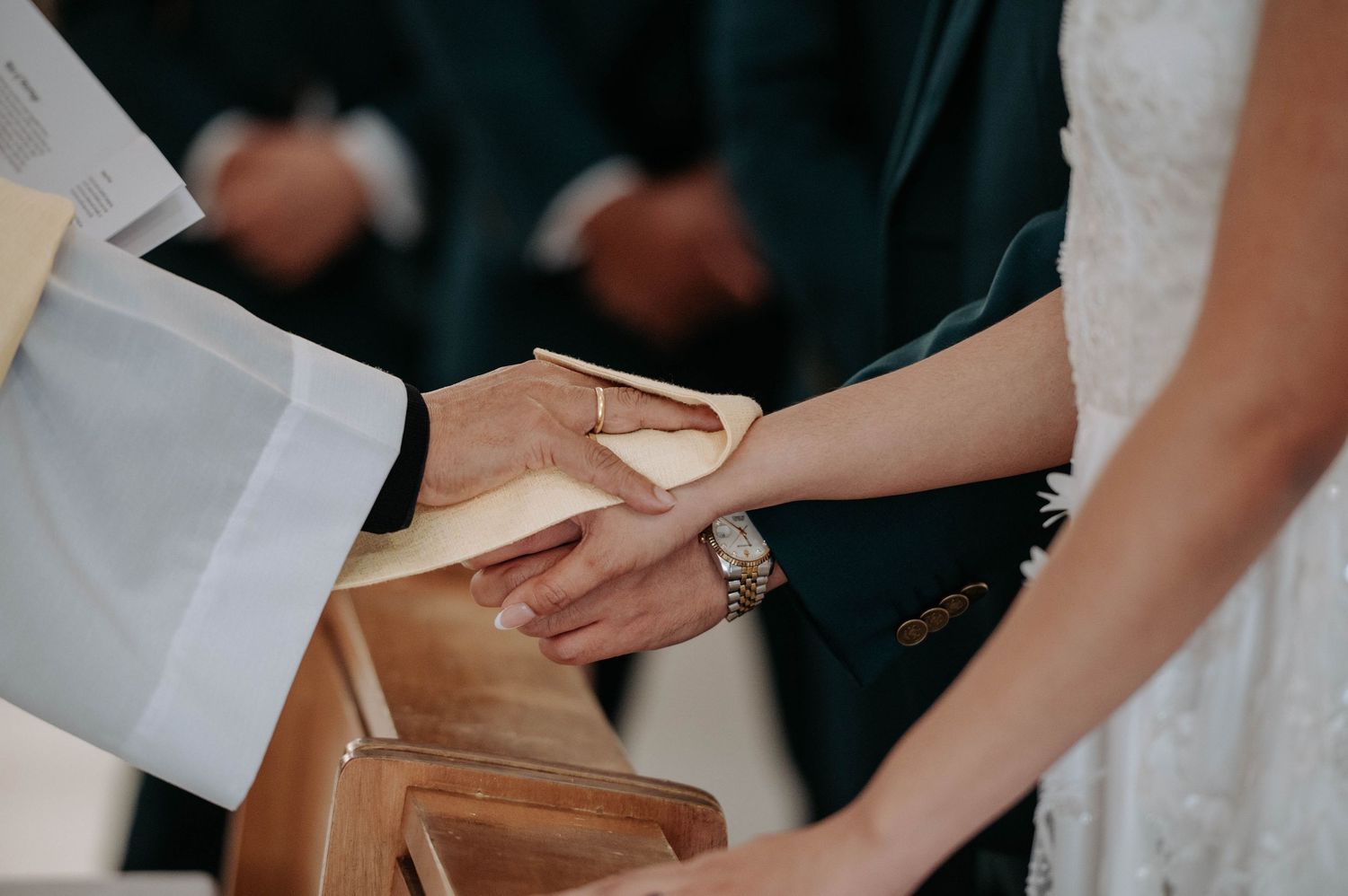 At a wedding ceremony, hands join together during an intimate exchange of rings.
