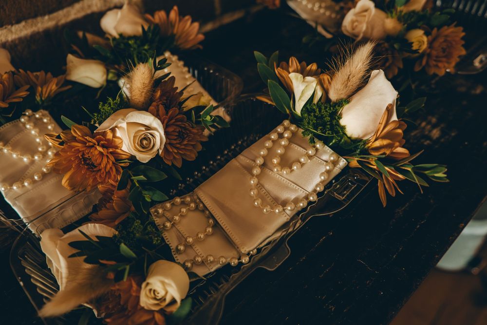 Wedding boutonnieres with white roses and sunflowers arranged on dark surface with delicate pearl details.