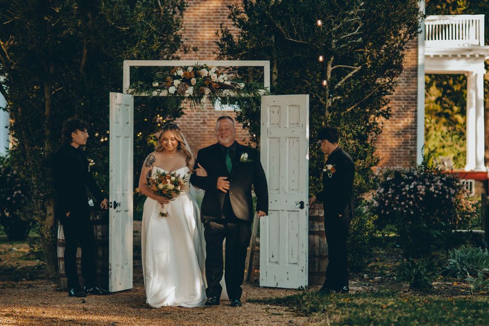 A couple exits through white vintage doors during an outdoor autumn wedding ceremony.
