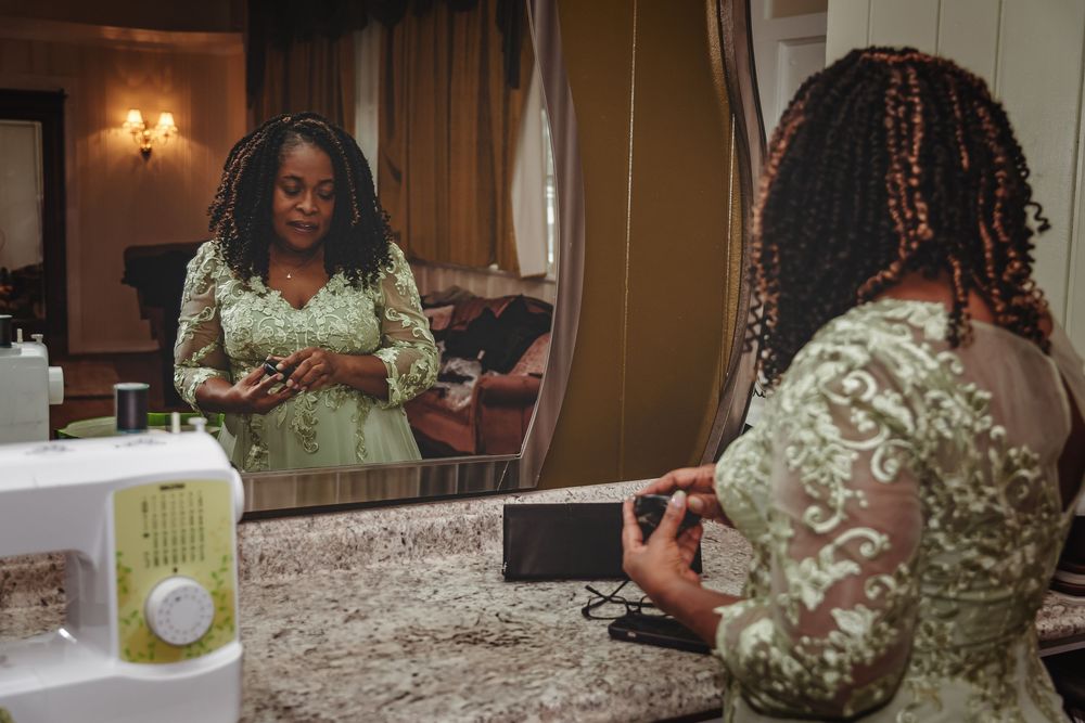 Someone wearing a green and white floral dress takes notes on a cell phone while sitting at a counter.
