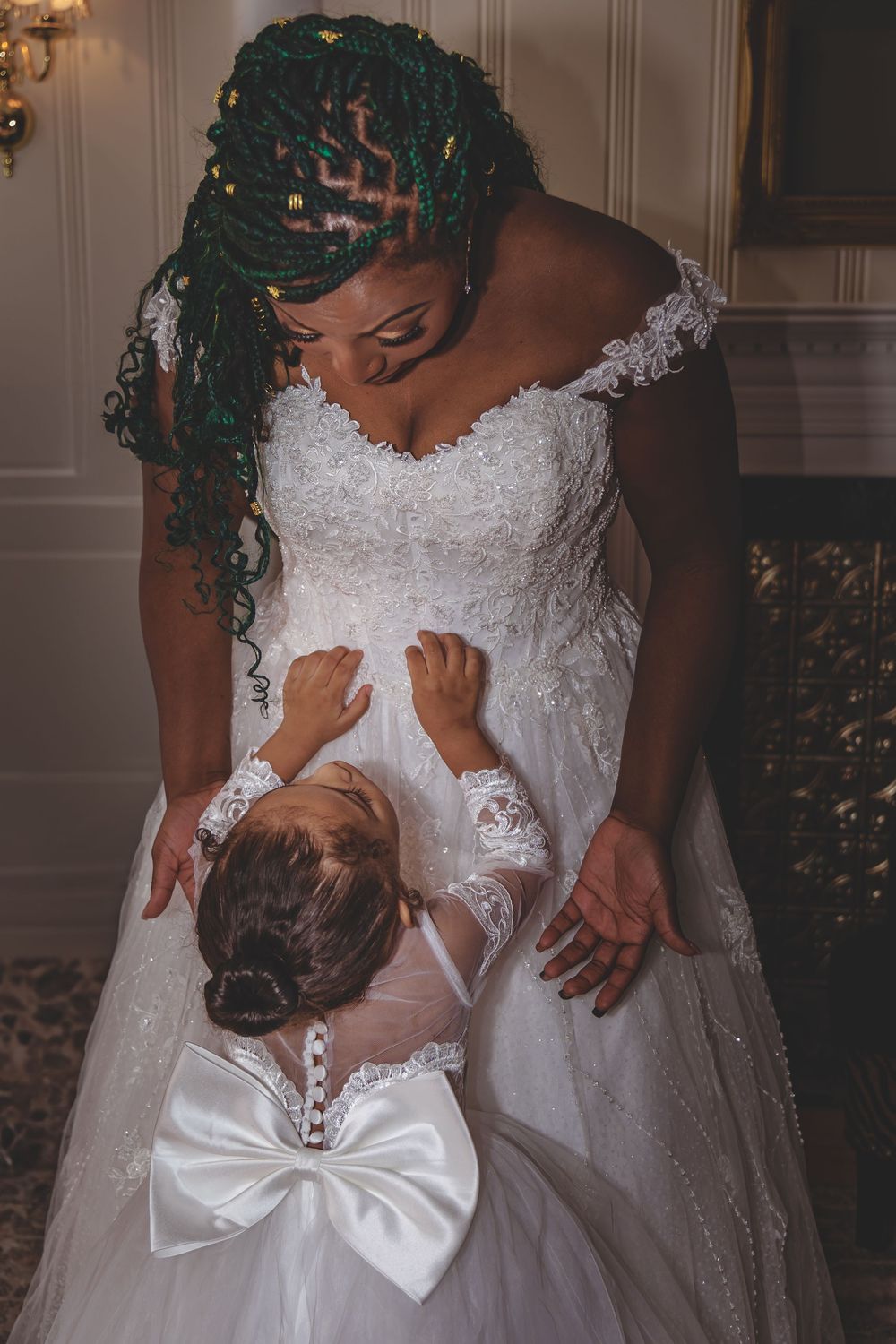 A tender moment between bride and flower girl in matching white lace dresses.
