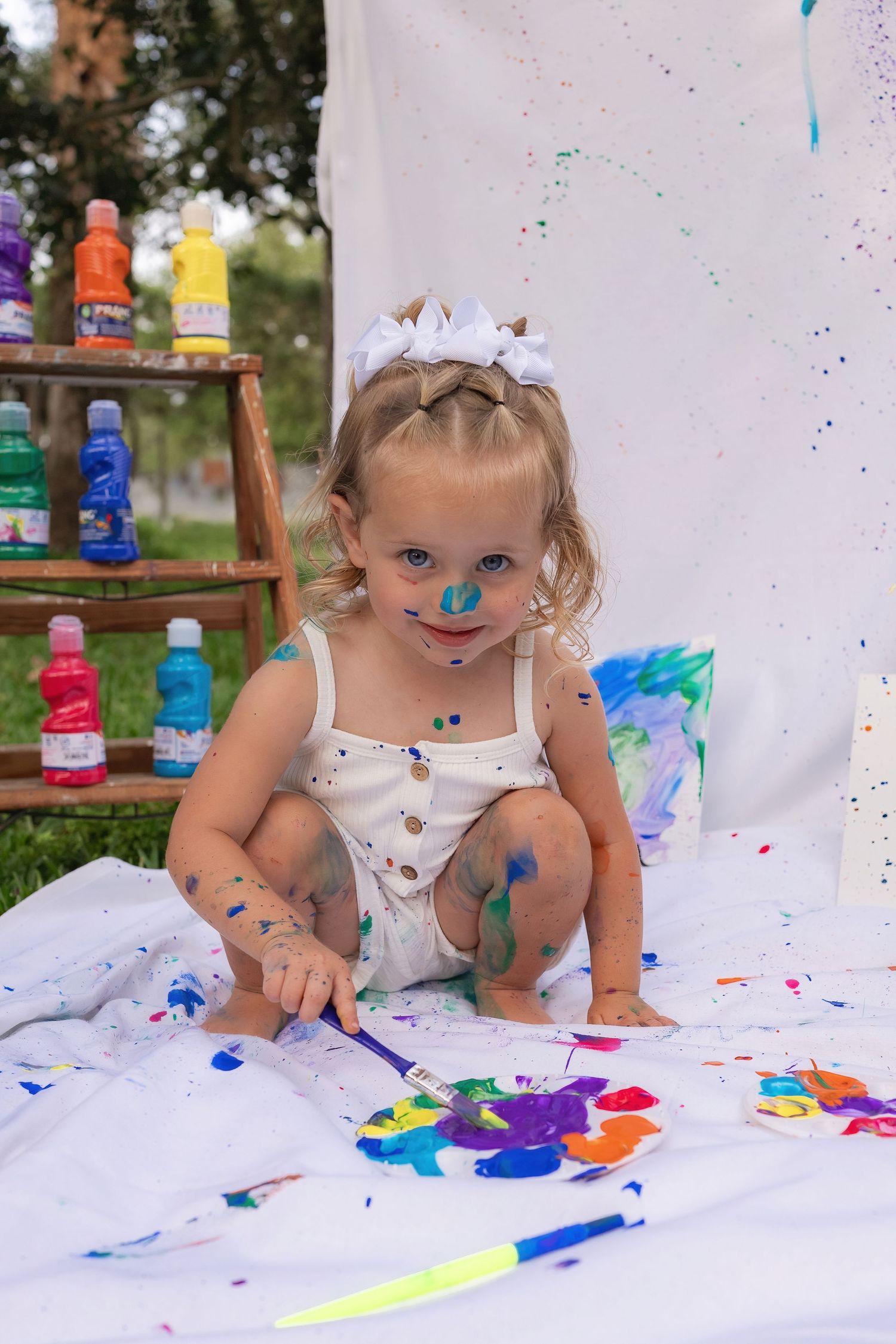 White canvas covered in colorful paint splatters during outdoor art session.