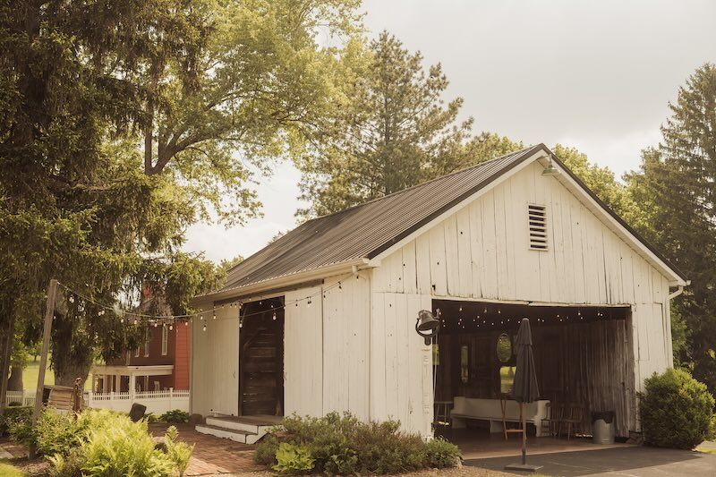 A white rustic barn with two entrances sits among trees at sunset, at shady elm farms near pittsburgh pa, one of many photo video spots.