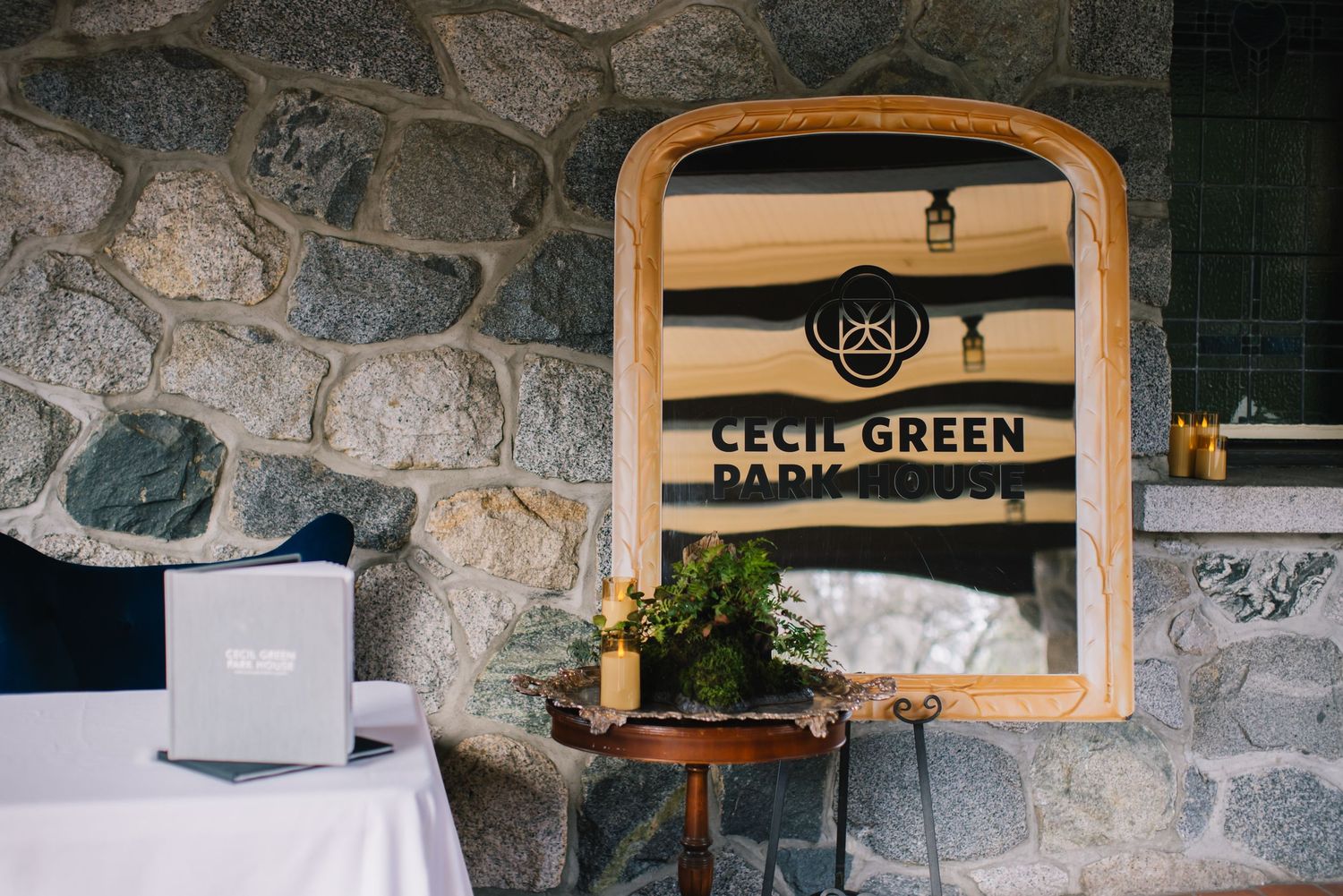 Rustic stone wall interior with wooden framed Cecil Green sign and table setting.