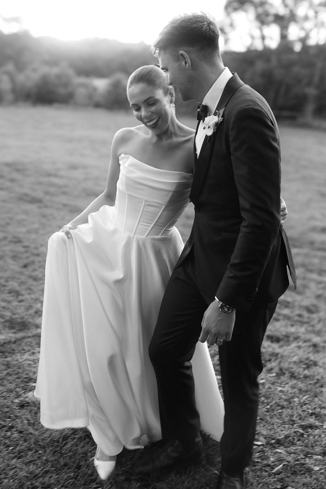 Joyful wedding couple sharing an intimate moment at sunset against a lush garden backdrop.