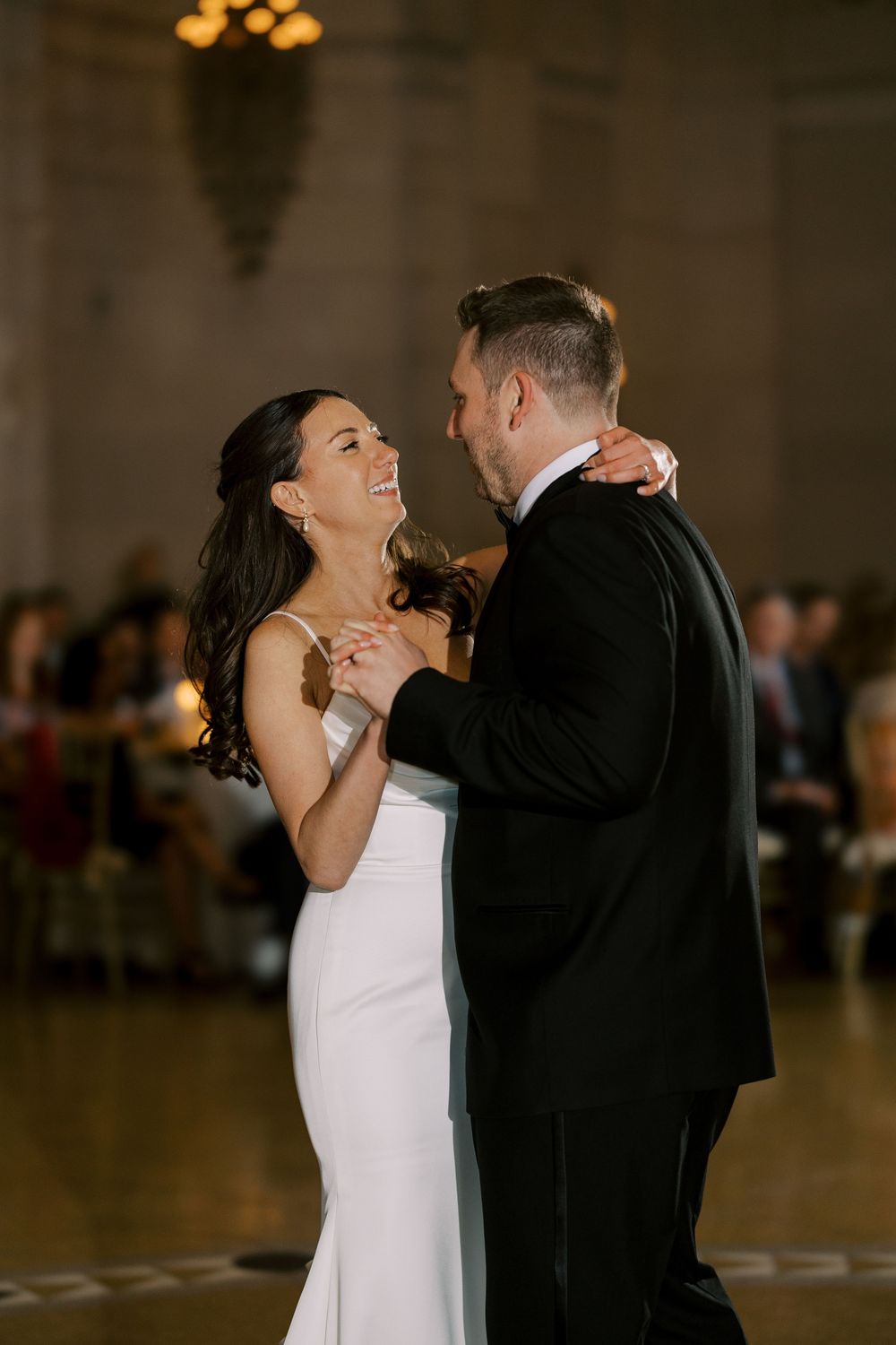 A couple shares their first dance together at their wedding reception in an elegant ballroom with warm lighting at Hall of Springs.