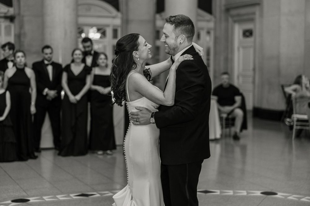 A couple shares their first dance as newlyweds at an elegant wedding reception while guests watch from the sidelines at Hall of Springs.