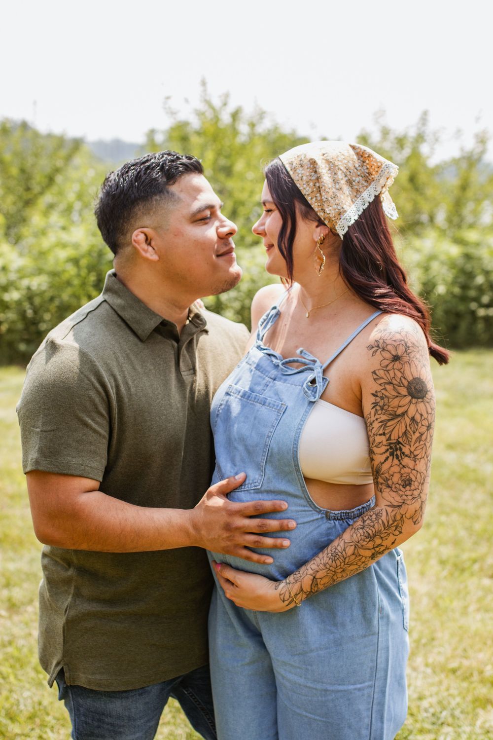 Intimate outdoor portrait of a couple with one wearing denim overalls and the other in a dark shirt.