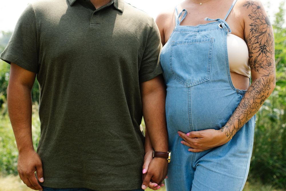 Romantic moment captured between couple in casual attire standing in a sunlit field.