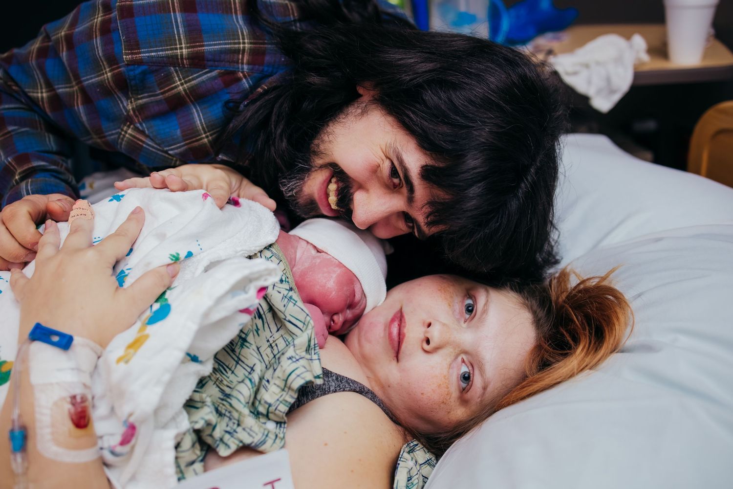 A tender moment of father and mother with newborn captured in hospital room after birth.