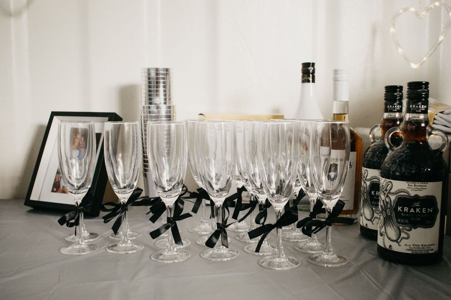 Crystal champagne flutes and wine glasses arranged on a table with liquor bottles in the background.