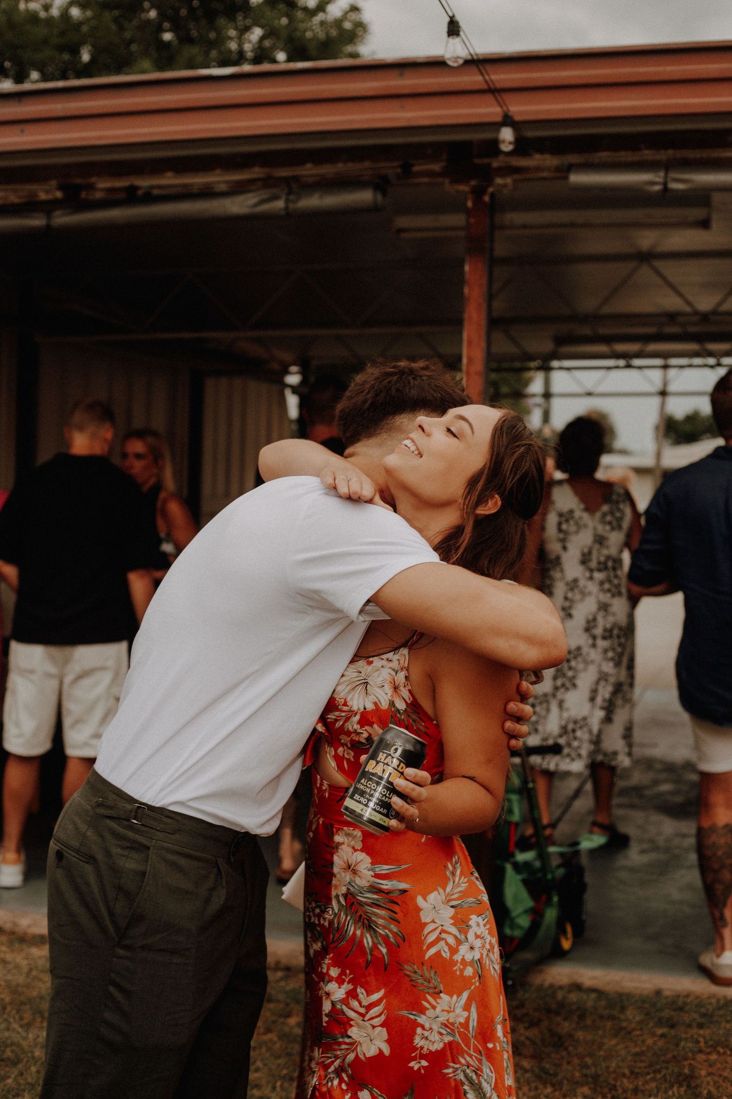 A couple embraces and dances together during an outdoor celebration under a covered patio.