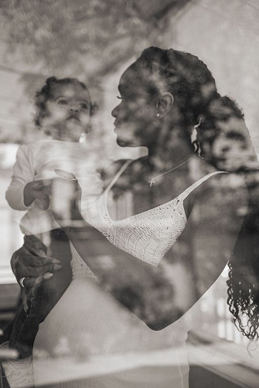 A heartfelt black and white double exposure photograph showing intimate interaction between parent and child through glass.