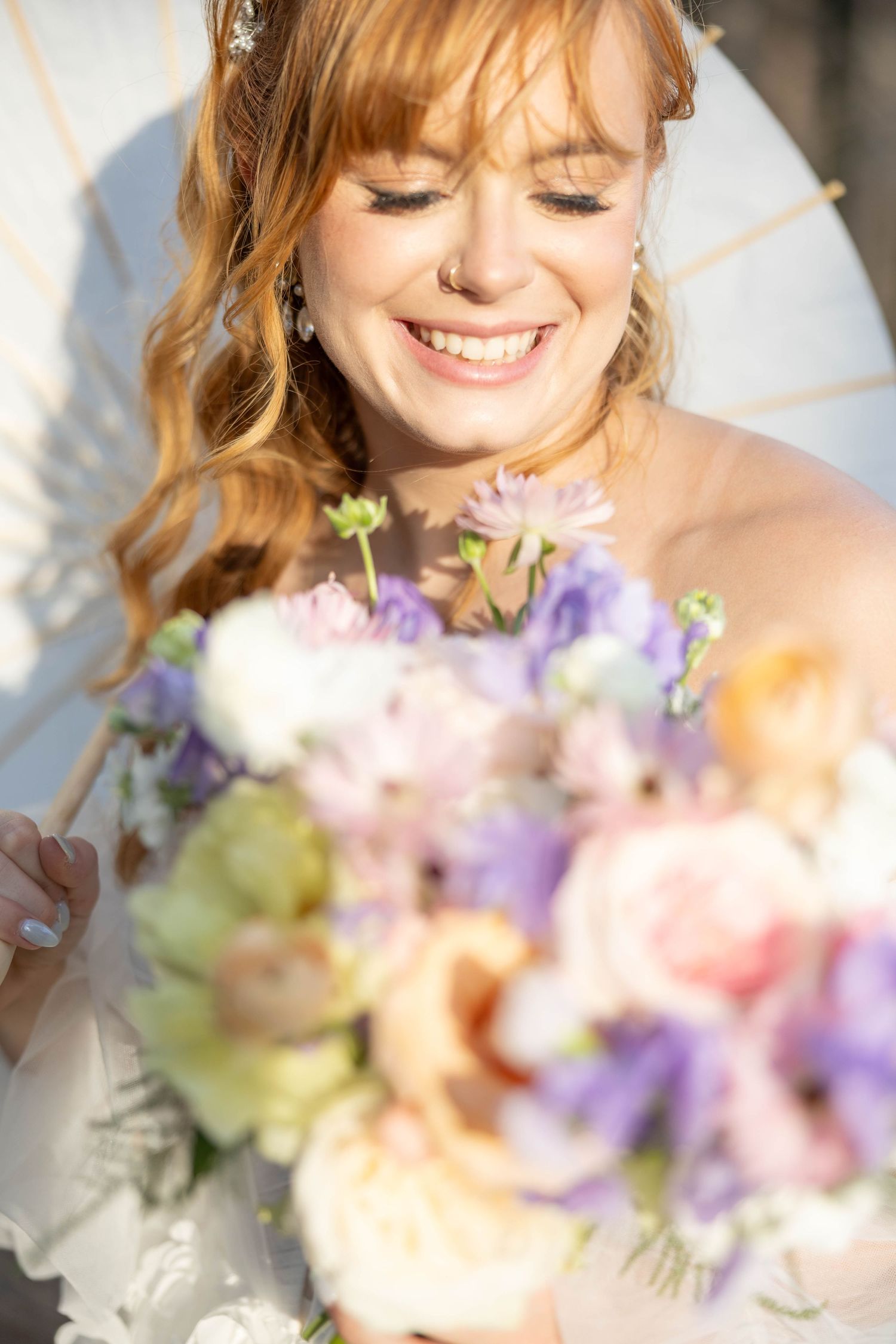 Close up of bride smiling with colorful wedding bouquet.