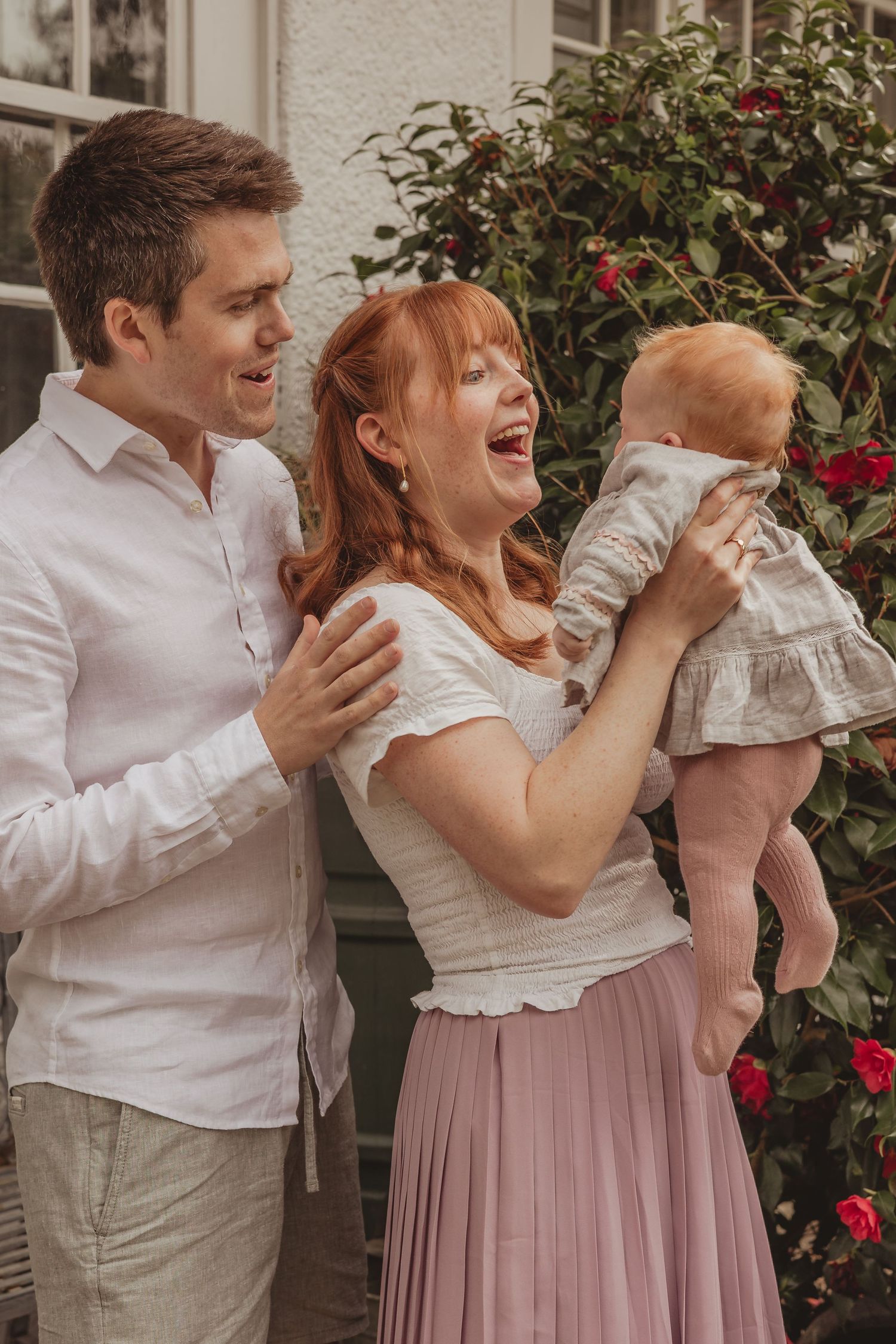 family photo where mum is throwing the baby in the air and laughing