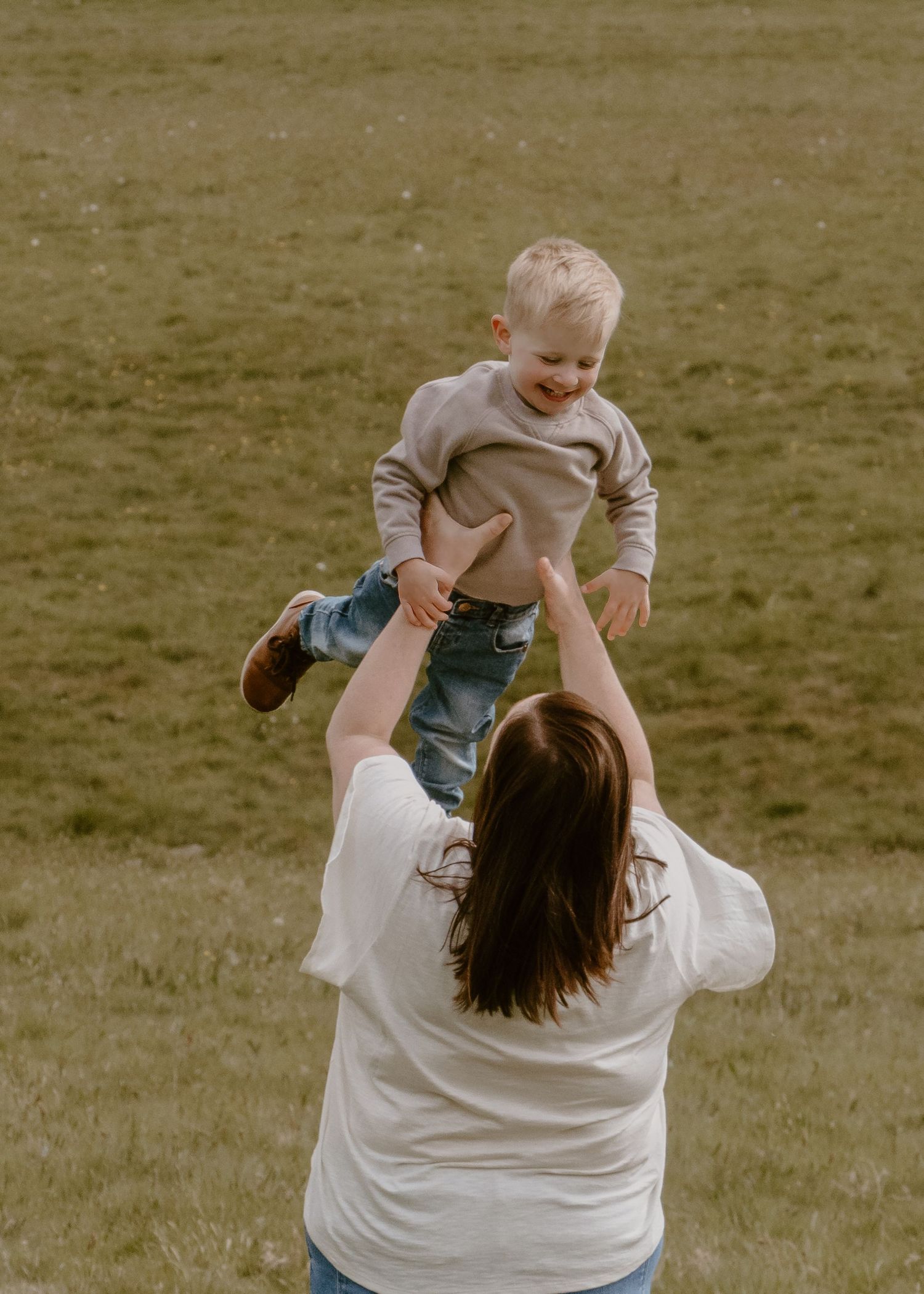 Wortley Hall - Playful moment of parent lifting child in air against grassy background.