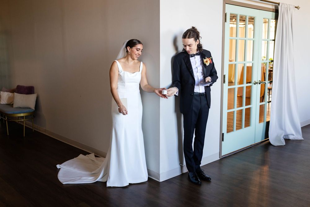 A couple in wedding attire standing against a wall during their first look moment.