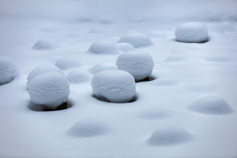Snow covered rocks create a minimalist winter landscape against a soft gray background.