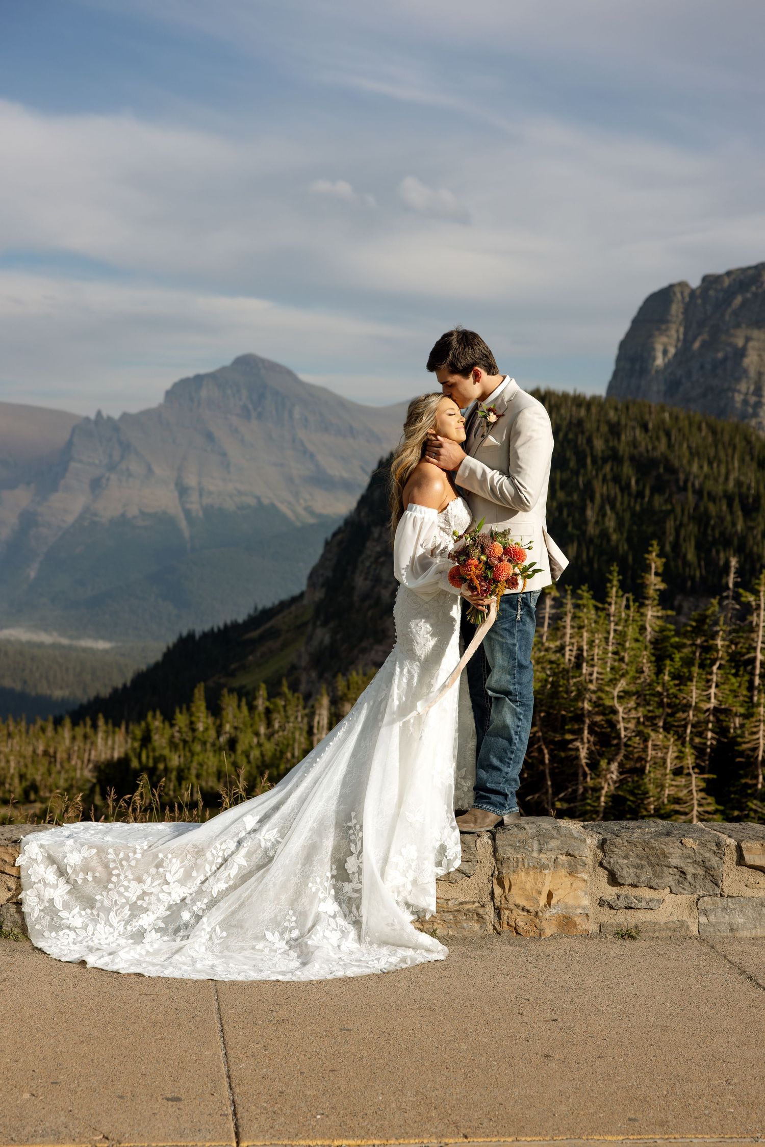A romantic wedding couple embraces against the majestic backdrop of mountain peaks in a national park.