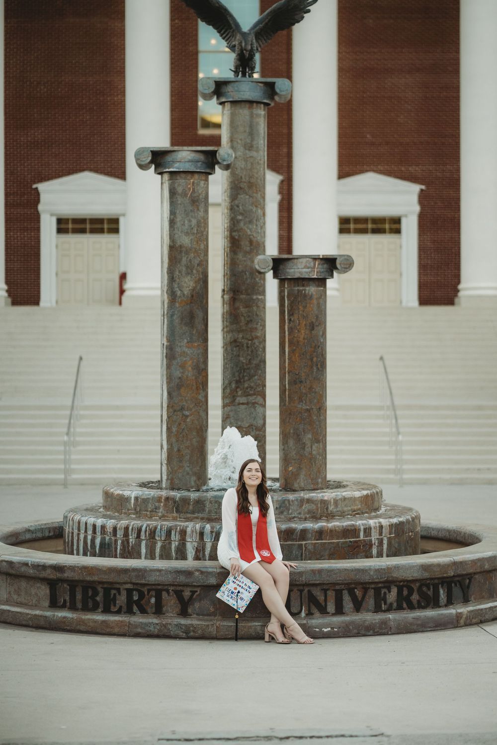 A formal portrait on stone steps features someone in red shoes against white columns.