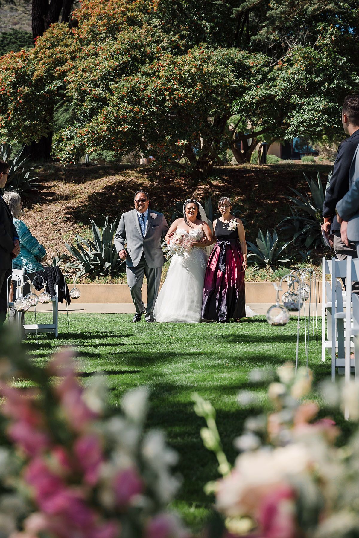 Floral wedding arch setup in the Presidio with the Golden Gate Bridge visible in the background through eucalyptus trees.