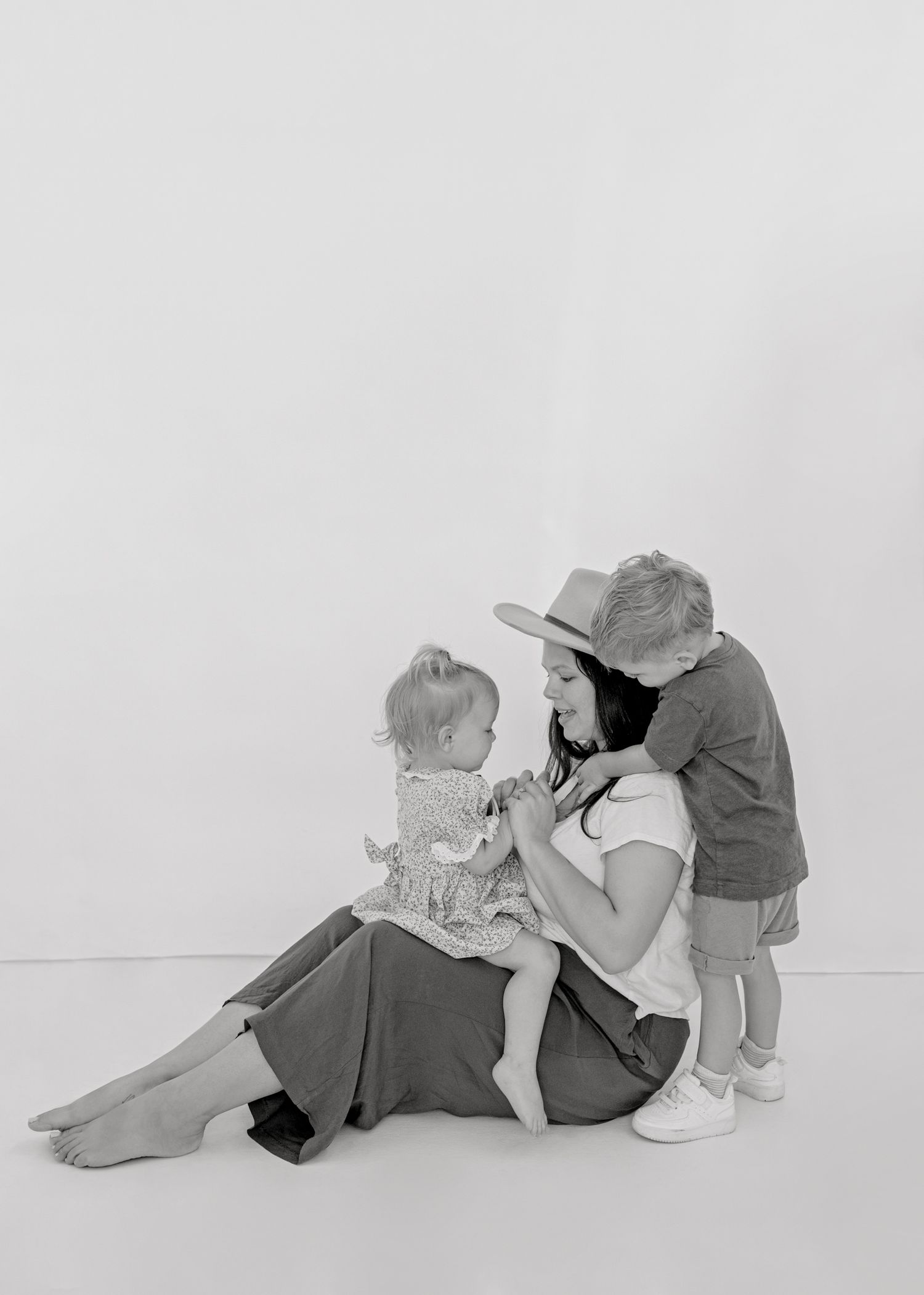 A black and white photo showing an intimate family moment as they sit together on the floor.