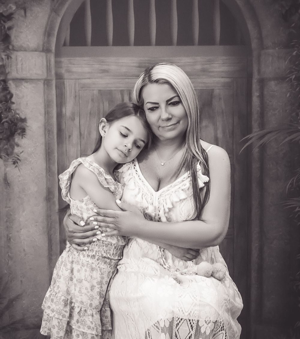 A touching black and white portrait of two people in white lace dresses sharing an intimate moment together.