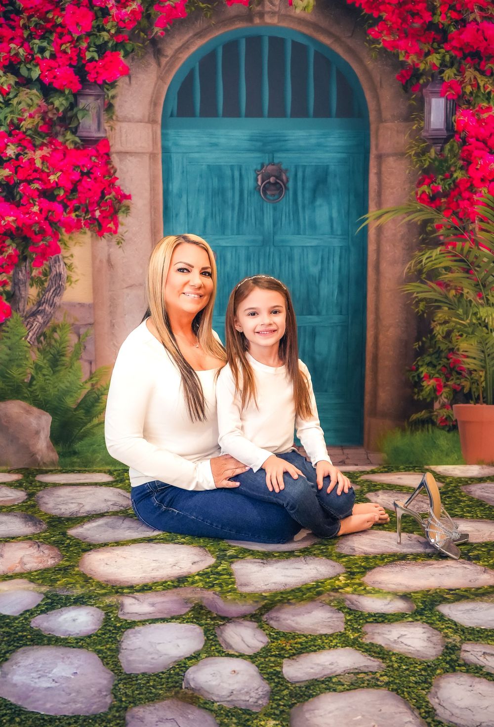 Beautiful outdoor portrait in front of a turquoise arched door with vibrant red bougainvillea flowers climbing the walls.