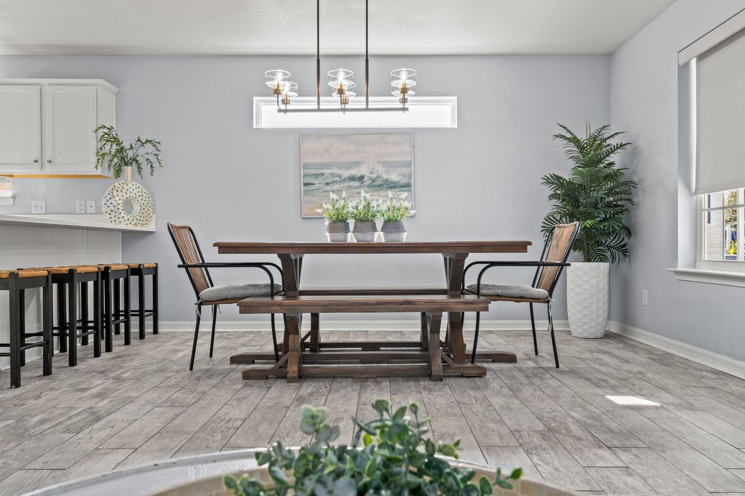 Modern dining room with farmhouse table, bench seating, and contemporary chandelier.