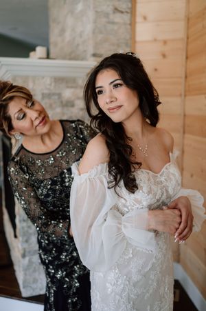 Bride in flowing white lace gown posing with companion in sparkling dark formal dress.