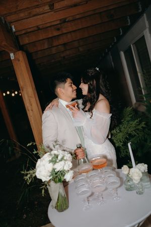 Couple sharing an intimate moment at their wedding reception with cocktails and white floral arrangements.