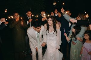 Wedding couple and guests celebrate with sparklers at a nighttime outdoor reception.