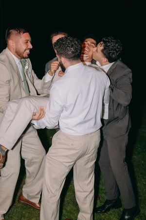 Group of well-dressed men laughing and having fun at outdoor evening celebration.