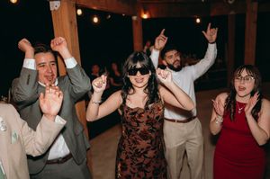 Enthusiastic wedding guests dancing and raising their arms at the reception.