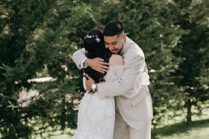 Tender embrace between newlyweds captured in a sunlit forest setting.