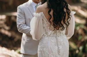 Detail shot of intricate lace wedding dress back design in natural forest lighting.