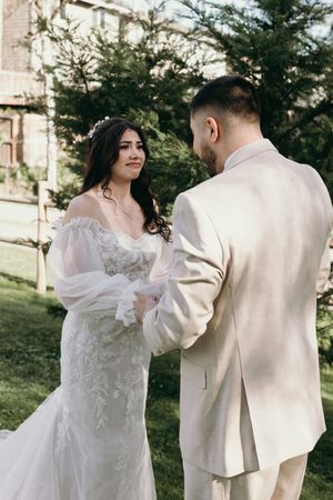 A couple exchanges vows during an outdoor wedding ceremony with evergreen trees in the background.