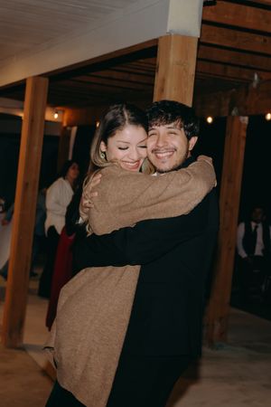 Two guests embracing and sharing a dance at an indoor wedding reception venue.