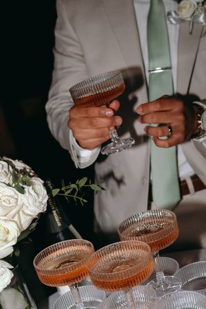 Elegant champagne coupe glasses being arranged with white floral decorations at a wedding reception.