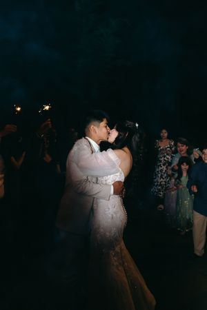A couple shares an intimate first dance at their wedding reception beneath sparklers held by guests.